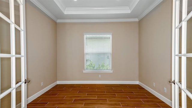 unfurnished room with dark hardwood / wood-style floors, ornamental molding, a raised ceiling, and french doors