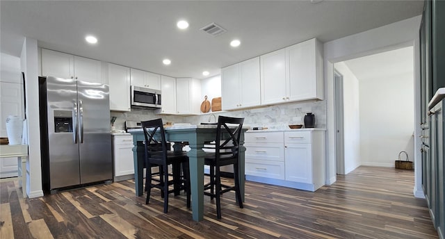 kitchen with stainless steel appliances, dark hardwood / wood-style floors, white cabinets, and backsplash