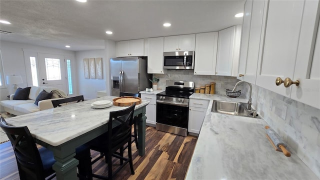 kitchen featuring sink, appliances with stainless steel finishes, white cabinetry, dark hardwood / wood-style floors, and light stone counters