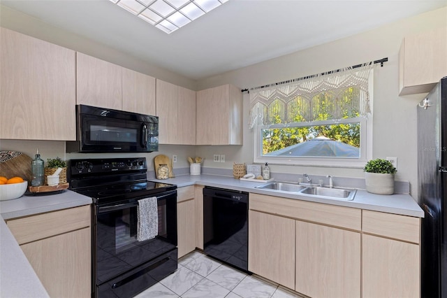 kitchen with a sink, black appliances, light brown cabinets, and light countertops