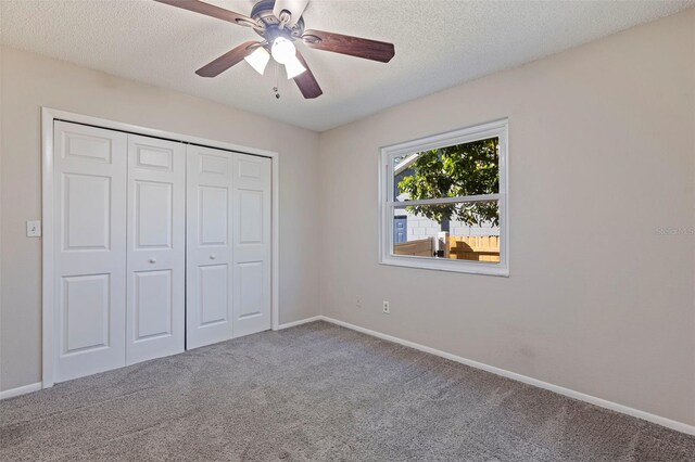 unfurnished bedroom featuring baseboards, ceiling fan, a closet, a textured ceiling, and carpet flooring