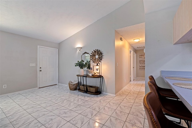 entryway featuring a textured ceiling, baseboards, and vaulted ceiling