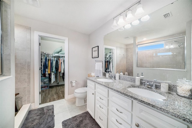 bathroom featuring vanity, tile patterned floors, toilet, and tiled shower