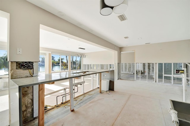 interior space with a water view, a healthy amount of sunlight, and concrete flooring