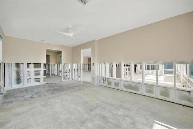 empty room with ceiling fan and concrete flooring