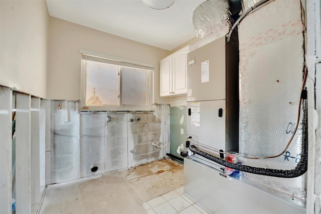 clothes washing area featuring cabinets and heating unit