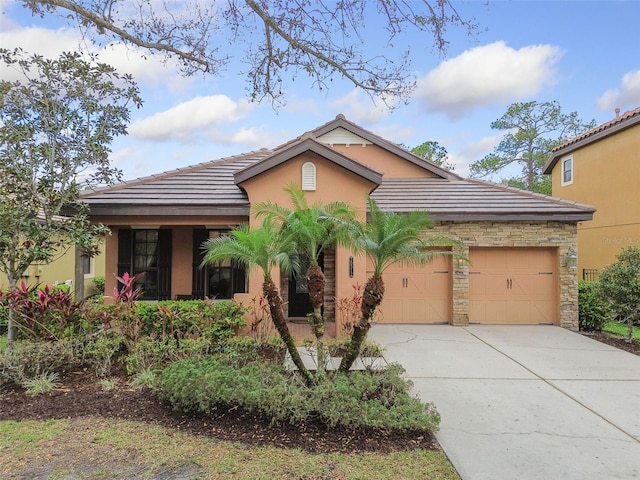 view of front of home featuring a tile roof, stucco siding, an attached garage, stone siding, and driveway