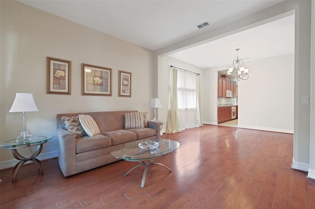 living area with a chandelier, dark wood-style flooring, visible vents, and baseboards