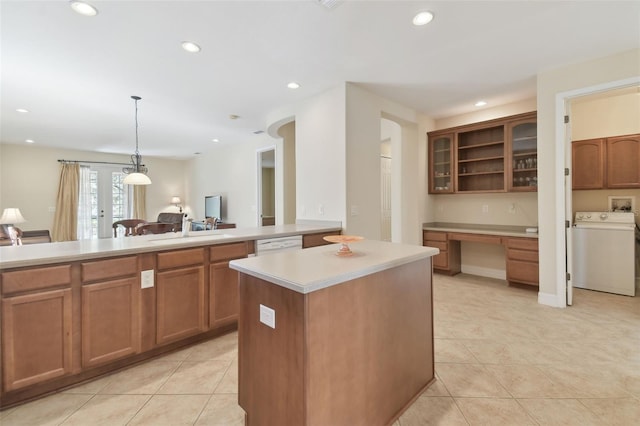 kitchen with washer / dryer, a center island, brown cabinets, and light countertops