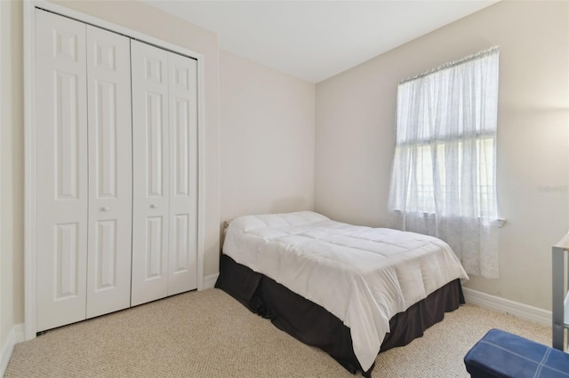 bedroom featuring a closet, light colored carpet, and baseboards