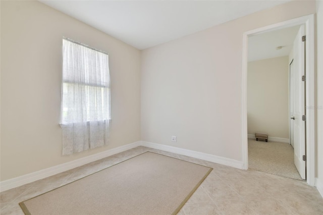 spare room with light tile patterned flooring and baseboards