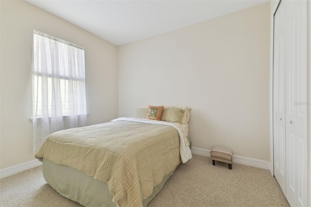 bedroom featuring a closet, light colored carpet, and baseboards