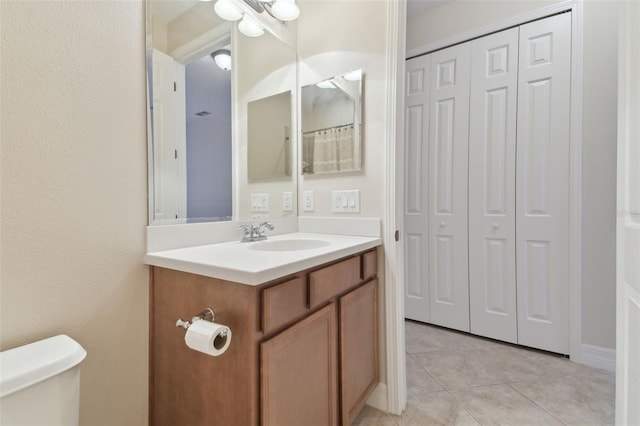 full bathroom featuring toilet, a closet, vanity, and tile patterned floors