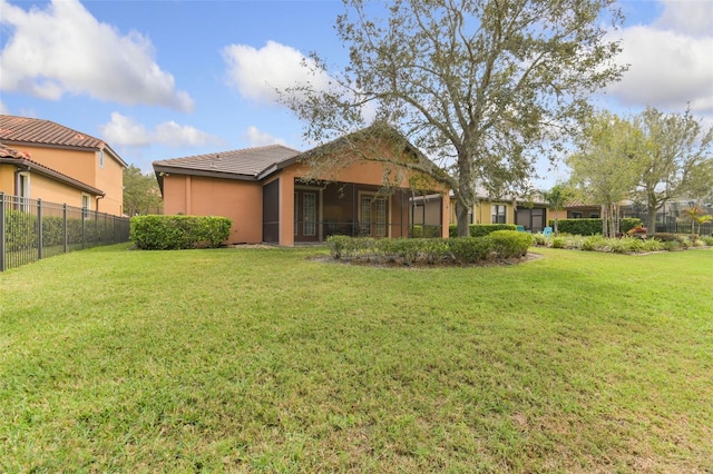 back of property with stucco siding, a lawn, a tiled roof, and fence