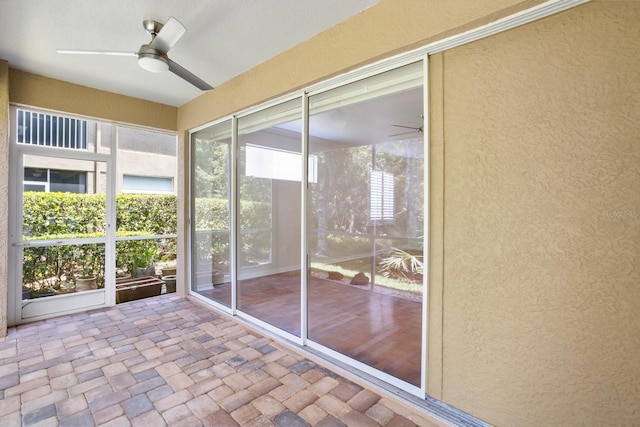 unfurnished sunroom featuring ceiling fan