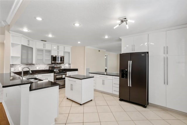 kitchen with sink, stainless steel appliances, tasteful backsplash, white cabinets, and a kitchen island