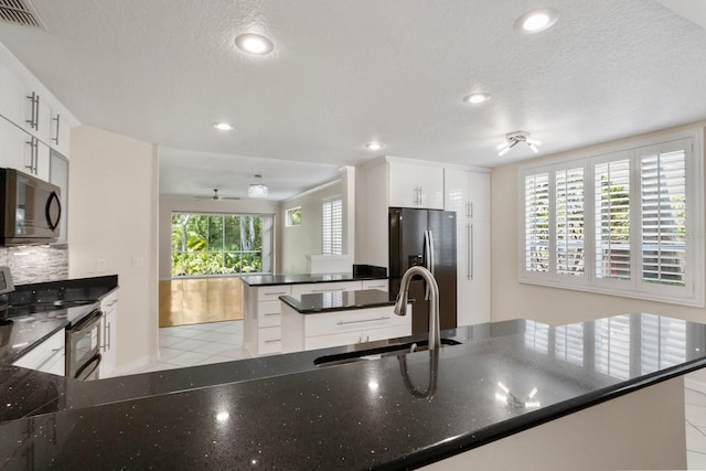 kitchen with sink, stainless steel fridge, white cabinetry, electric range, and kitchen peninsula