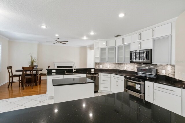 kitchen featuring light tile patterned flooring, sink, white cabinetry, appliances with stainless steel finishes, and backsplash