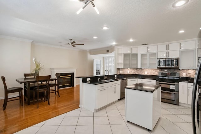 kitchen featuring white cabinetry, sink, light tile patterned floors, kitchen peninsula, and stainless steel appliances