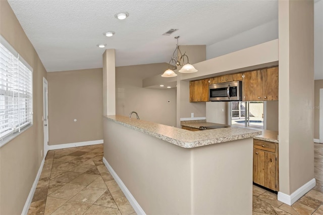 kitchen featuring pendant lighting, kitchen peninsula, vaulted ceiling, and a textured ceiling