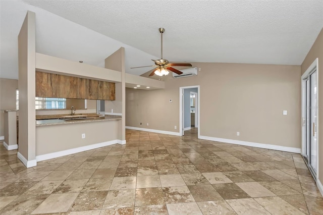 kitchen with lofted ceiling, sink, a wall mounted AC, ceiling fan, and a textured ceiling