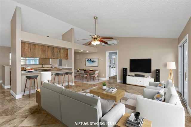 living room with lofted ceiling, a textured ceiling, a wealth of natural light, and a wall mounted AC