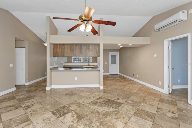 kitchen with vaulted ceiling, sink, a wall unit AC, ceiling fan, and a textured ceiling