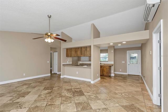 kitchen featuring lofted ceiling, ceiling fan, kitchen peninsula, a textured ceiling, and a wall unit AC