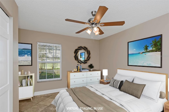 tiled bedroom featuring ceiling fan and a textured ceiling