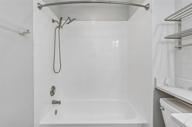 bathroom with tiled shower / bath combo and toilet