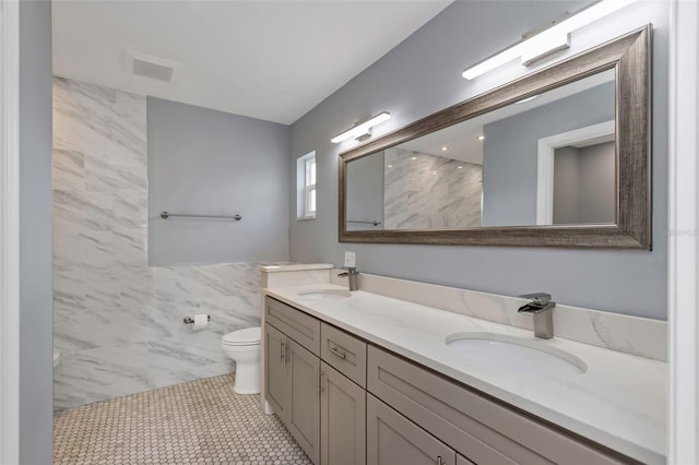 bathroom with vanity, a shower, tile walls, and toilet