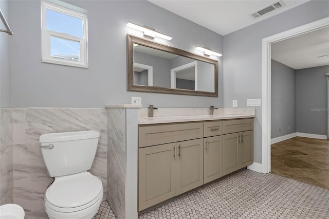 bathroom featuring vanity, tile walls, and toilet