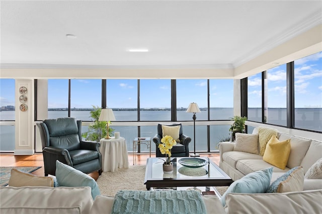 living room with a water view, ornamental molding, a wealth of natural light, and light wood-type flooring