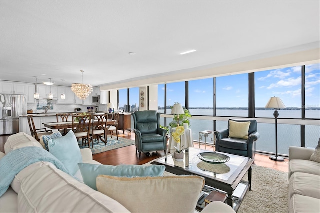 living room featuring a water view, hardwood / wood-style floors, and a notable chandelier