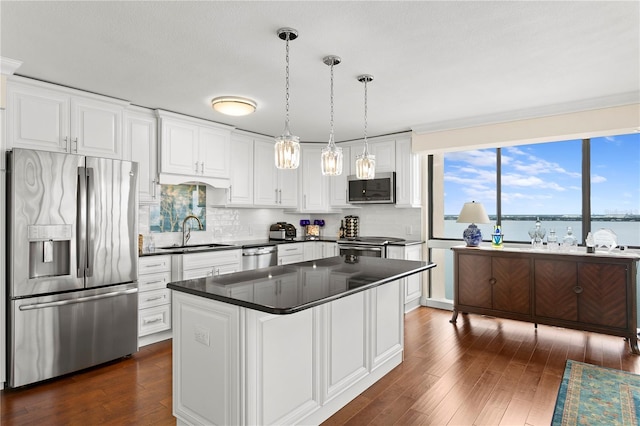 kitchen featuring pendant lighting, sink, appliances with stainless steel finishes, a water view, and white cabinets