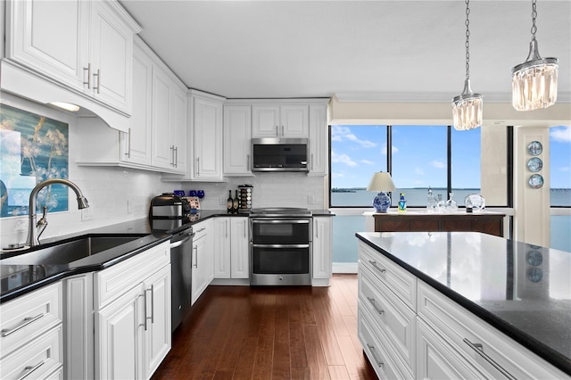 kitchen featuring stainless steel appliances, sink, pendant lighting, and white cabinets