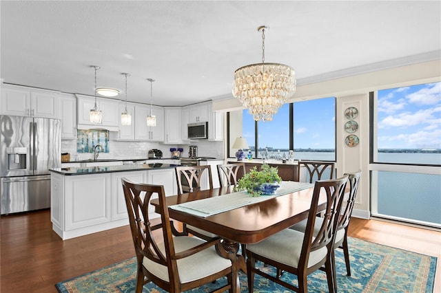 dining space with crown molding, a water view, sink, and dark hardwood / wood-style floors