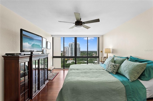 bedroom with dark hardwood / wood-style flooring, expansive windows, and ceiling fan