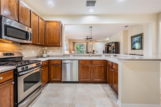 kitchen featuring appliances with stainless steel finishes, sink, decorative backsplash, light tile patterned floors, and kitchen peninsula