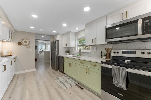 kitchen featuring sink, tasteful backsplash, green cabinetry, stainless steel appliances, and white cabinets