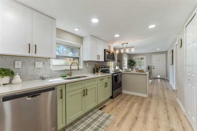 kitchen featuring pendant lighting, sink, stainless steel appliances, green cabinetry, and decorative backsplash