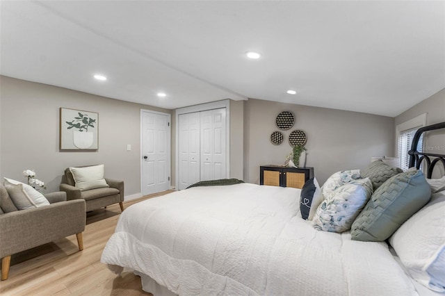 bedroom featuring vaulted ceiling, light hardwood / wood-style floors, and a closet