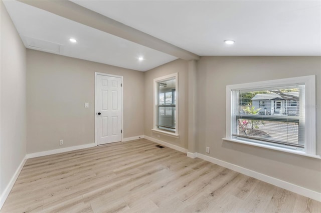 spare room with lofted ceiling with beams and light wood-type flooring