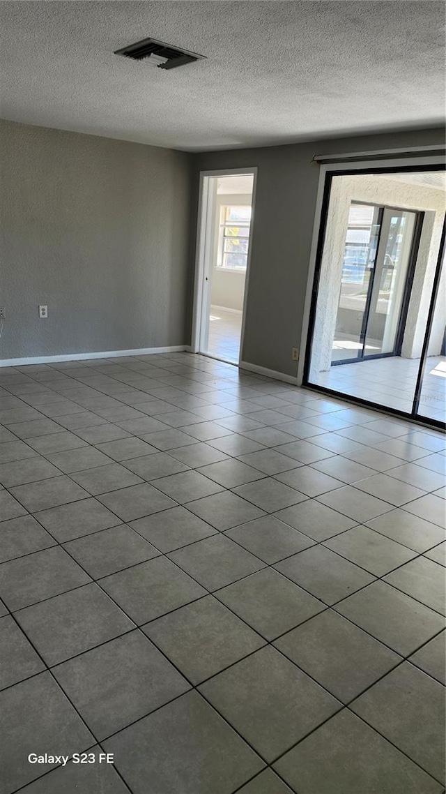 tiled empty room featuring a textured ceiling