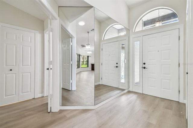 foyer with ceiling fan, a high ceiling, and light wood-type flooring