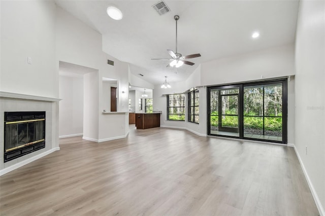 unfurnished living room with a tile fireplace, high vaulted ceiling, ceiling fan, and light hardwood / wood-style floors