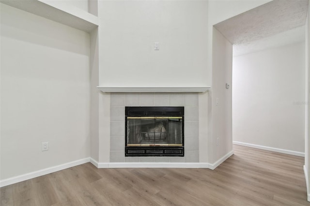 interior details with a tiled fireplace and hardwood / wood-style floors