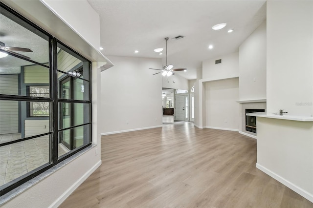 unfurnished living room with vaulted ceiling, ceiling fan, and light hardwood / wood-style floors