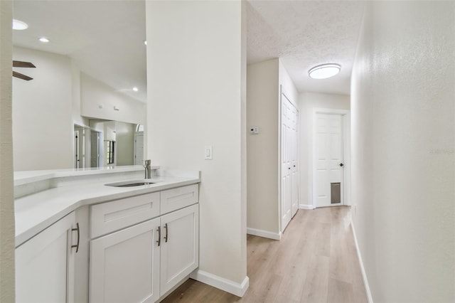 bathroom featuring lofted ceiling, hardwood / wood-style flooring, vanity, ceiling fan, and a textured ceiling