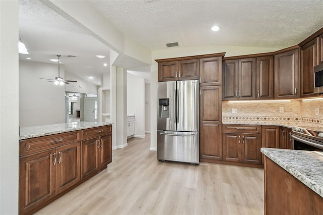 kitchen featuring light stone counters, lofted ceiling, and stainless steel appliances